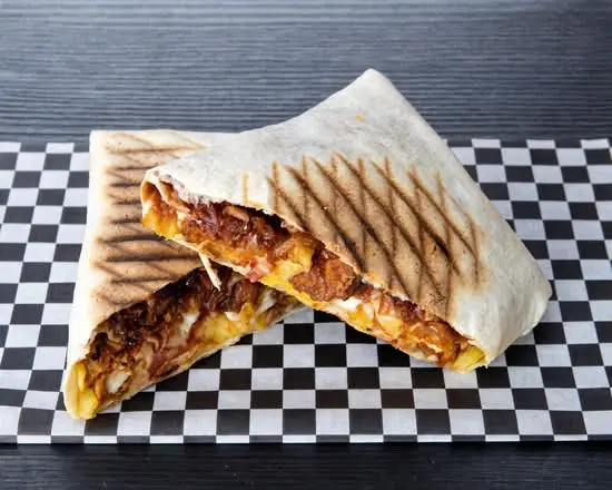 Taco Torreño partido por la mitad sobre papel de cuadros, con tenders de pollo y queso fundido a la vista